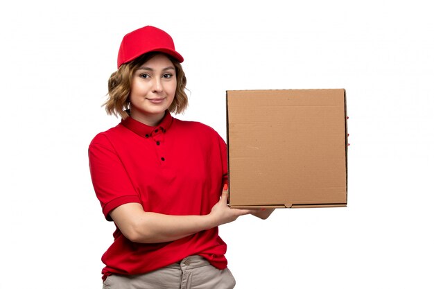 A front view young female courier female worker of food delivery service holding food delivery package smiling on white