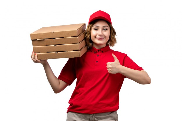 A front view young female courier female worker of food delivery service holding food delivery packages smiling on white