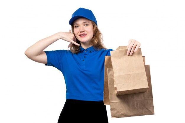 A front view young female courier female worker of food delivery service holding food delivery packages smiling on white