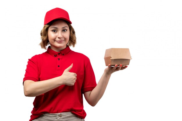 A front view young female courier female worker of food delivery service holding food package and smiling on white