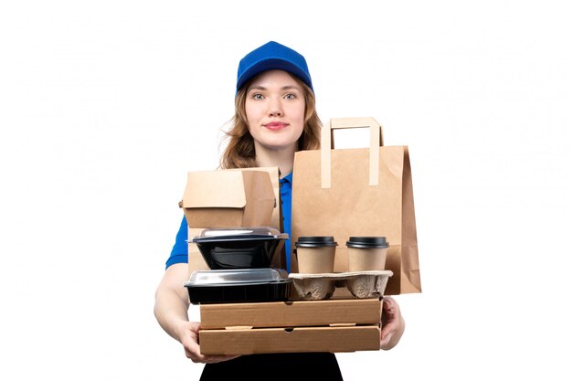 A front view young female courier female worker of food delivery service holding food packages and boxes on white