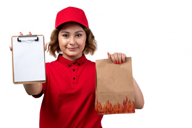 Foto gratuita una giovane lavoratrice femminile del corriere femminile di vista frontale del blocco note della tenuta di servizio di distribuzione di alimenti e del pacchetto dell'alimento che sorride sul bianco