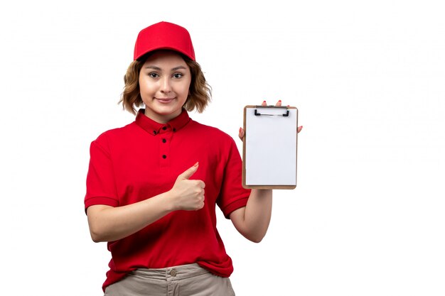 A front view young female courier female worker of food delivery service holding notepad for signatures and smiling on white