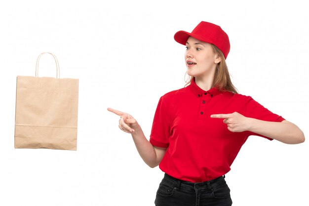 A front view young female courier female worker of food delivery service smiling around thrown food delivery package on white