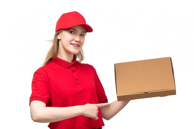 A front view young female courier female worker of food delivery service smiling holding box with food on white