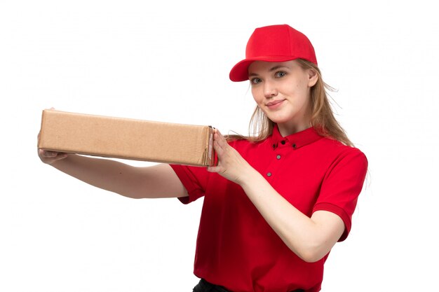 A front view young female courier female worker of food delivery service smiling holding box with food on white