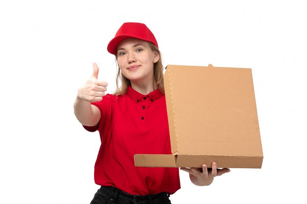 A front view young female courier female worker of food delivery service smiling holding box with food on white