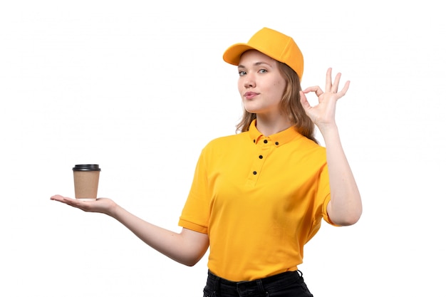 A front view young female courier female worker of food delivery service smiling holding coffee cup on white