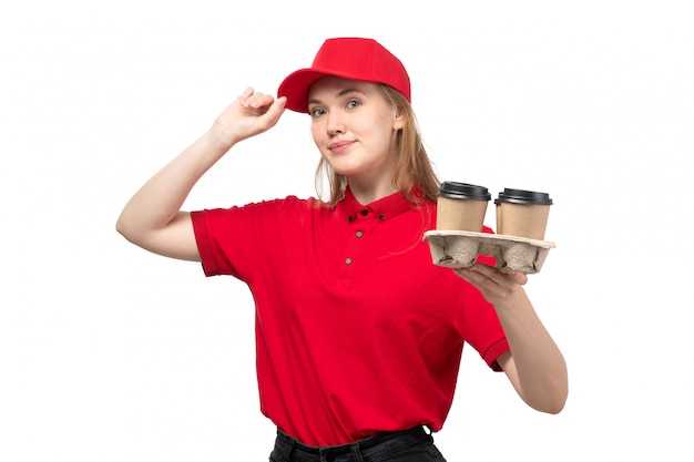 A front view young female courier female worker of food delivery service smiling holding cupf of coffee on white