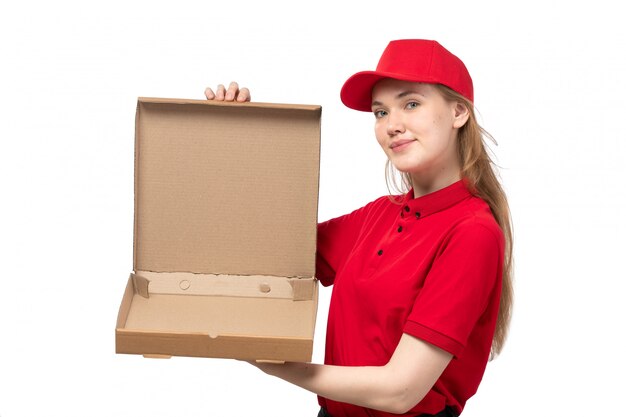 A front view young female courier female worker of food delivery service smiling holding an empty box with food on white