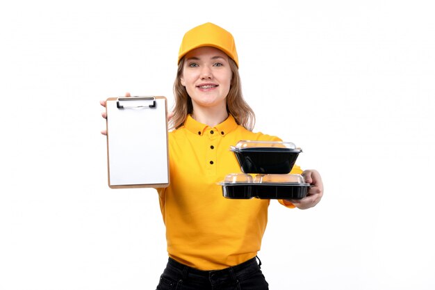 A front view young female courier female worker of food delivery service smiling holding notepad and bowls with food on white