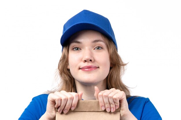 A front view young female courier female worker of food delivery service smiling holding package with food on white