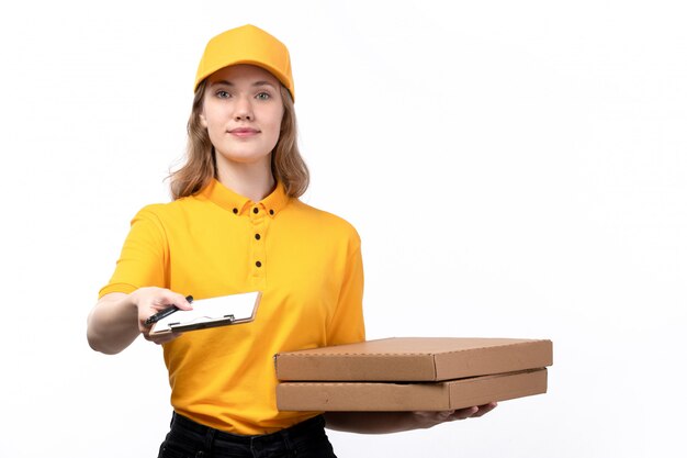 Una giovane lavoratrice femminile del corriere femminile di vista frontale delle scatole e del blocco note sorridenti della pizza della tenuta di servizio di distribuzione di alimenti su bianco