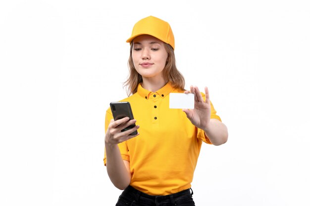 A front view young female courier female worker of food delivery service smiling holding using a phone and white card on white