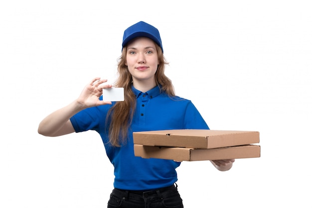 A front view young female courier female worker of food delivery service smiling holding white card and delivery boxes on white