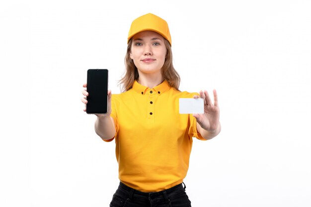 A front view young female courier female worker of food delivery service smiling holding white card and smartphone on white