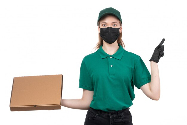 緑の制服の黒い手袋とフードデリバリーパッケージの配信を保持している黒いマスクの正面の若い女性の宅配便