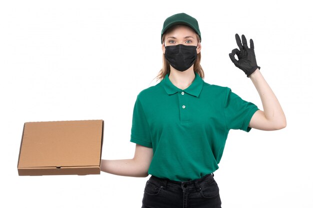녹색 유니폼 검은 장갑과 음식 배달 패키지를 들고 검은 마스크에 전면보기 젊은 여성 택배 제공