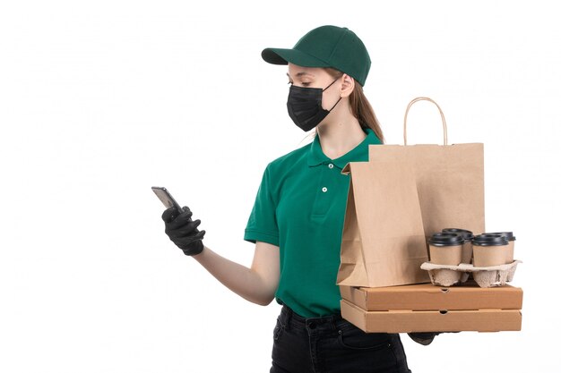 녹색 유니폼 검은 장갑과 음식 배달 패키지를 들고 검은 마스크에 전면보기 젊은 여성 택배 제공