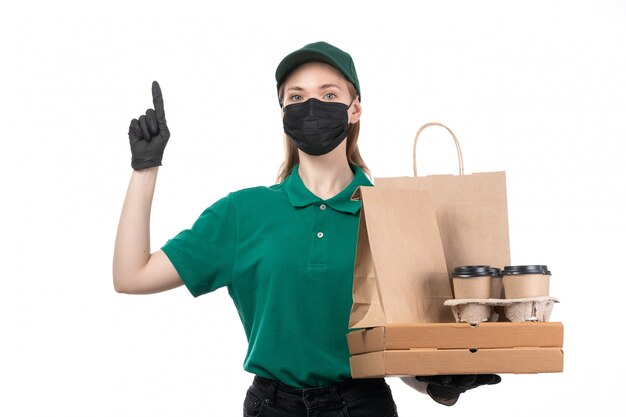 緑の制服の黒い手袋とフードデリバリーパッケージを提供する保持している黒いマスクの正面の若い女性宅配便