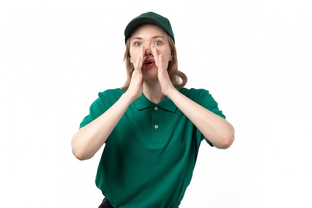 A front view young female courier in green uniform covering her mouth trying to scream on white