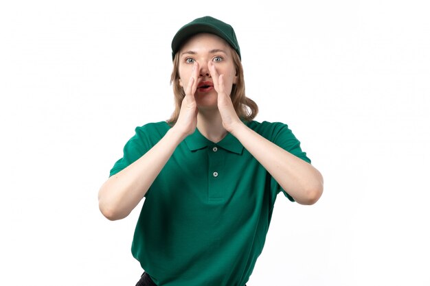 Вид спереди молодая женщина-курьер в зеленой форме, прикрывая рот, пытаясь закричать на белом