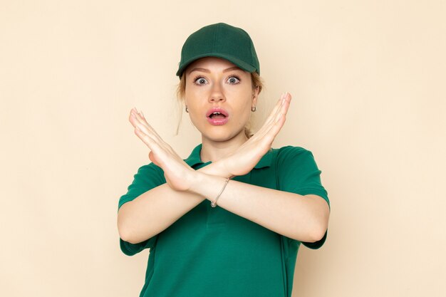 Giovane corriere femminile di vista frontale in uniforme verde e mantello verde che posa sull'uniforme da lavoro della ragazza di lavoro dello spazio leggero