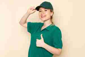 Free photo front view young female courier in green uniform and green cape posing with smile on the light space   job lady