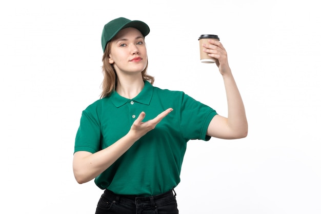 A front view young female courier in green uniform holding coffee cup on white