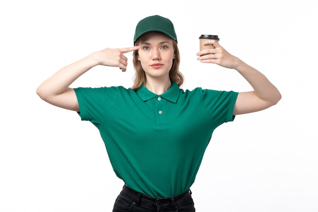 A front view young female courier in green uniform holding coffee cup on white