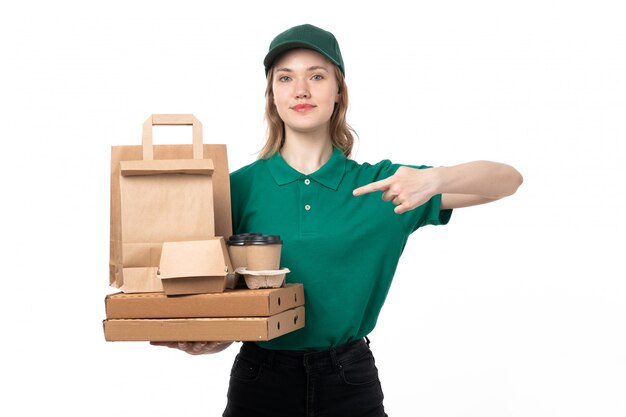 A front view young female courier in green uniform holding coffee cups packages and smiling