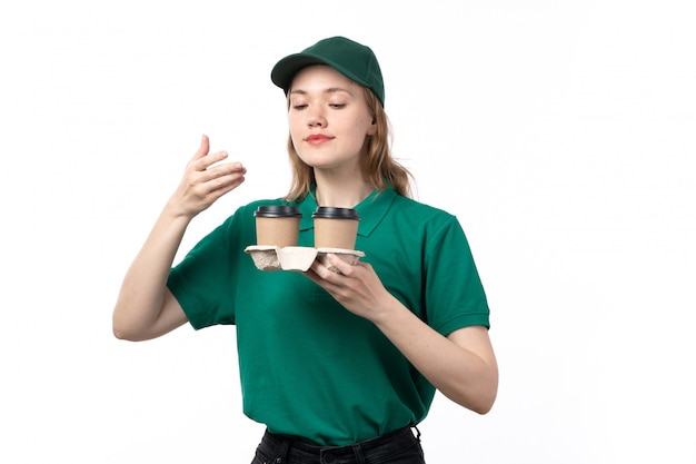 彼らの香りの臭いがするコーヒーカップを保持している緑の制服を着た正面若い女性宅配便