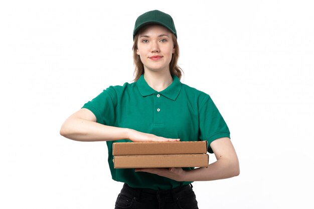 Молодая женщина-курьер в зеленой форме, держащая коробки для пиццы и улыбаясь, вид спереди