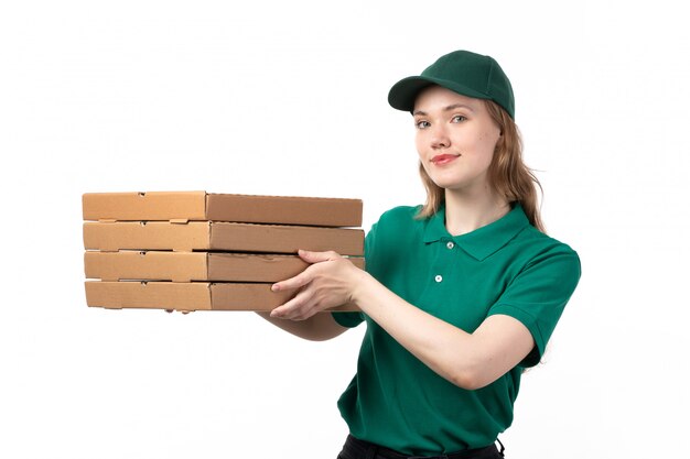 A front view young female courier in green uniform holding pizza delivery boxes smiling