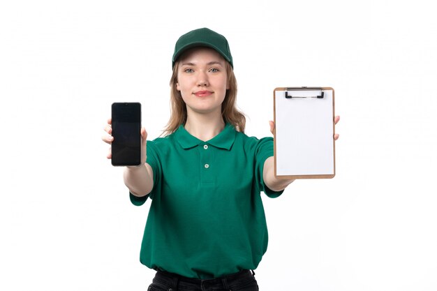 スマートフォンとメモ帳の笑顔を保持している緑の制服を着た正面若い女性宅配便