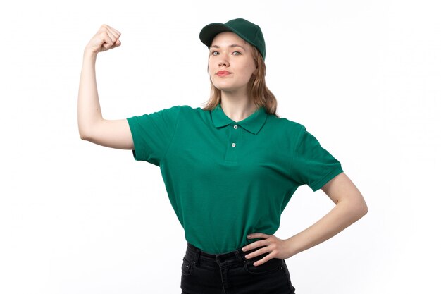 Молодая женщина-курьер в зеленой форме позирует, сгибаясь и улыбаясь, вид спереди