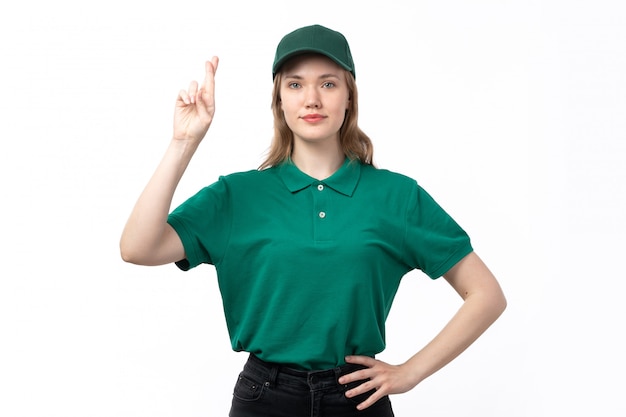 A front view young female courier in green uniform posing with crossed fingers smiling