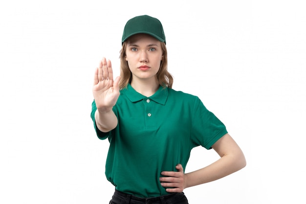 Молодая женщина-курьер в зеленой форме, вид спереди, показывает знак остановки