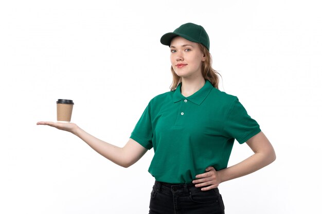 A front view young female courier in green uniform smiling holding coffee cup