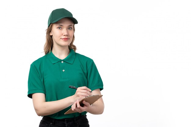 A front view young female courier in green uniform smiling holding notepad for signatures