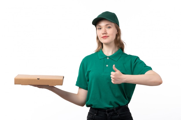 A front view young female courier in green uniform smiling holding package with food showing like sign