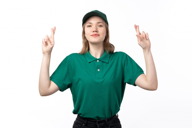 A front view young female courier in green uniform smiling posing with crossed fingers