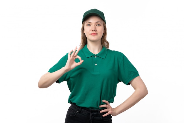 A front view young female courier in green uniform smiling and showign alright sign