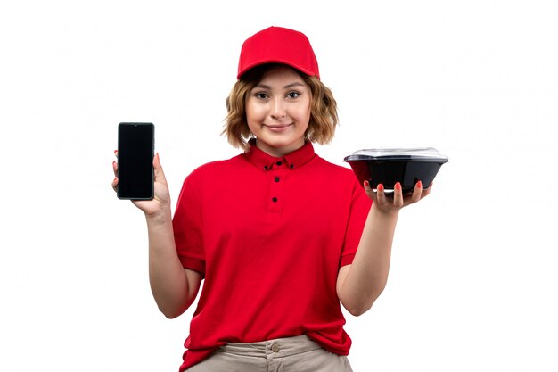 Un giovane corriere femminile di vista frontale in ciotola rossa della tenuta del cappuccio della camicia rossa con il telefono sorridente della tenuta dell'alimento