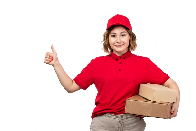 Молодая женщина-курьер в красной рубашке и красной кепке, держащая коробки доставки, вид спереди