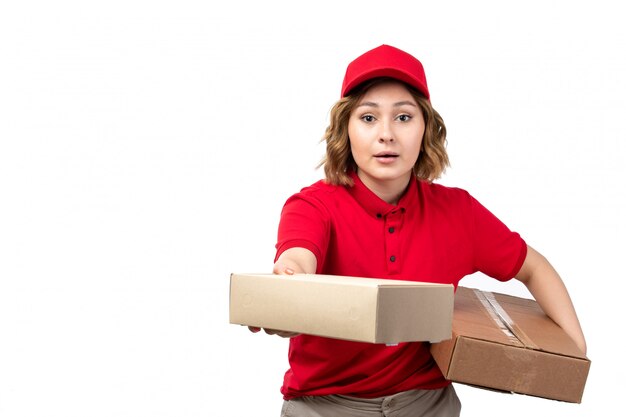 A front view young female courier in red shirt red cap holding delivery packages