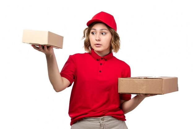 A front view young female courier in red shirt red cap holding delivery packages