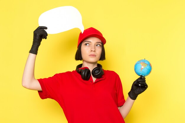A front view young female courier in red uniform black gloves and red cap holding white sign and little globe
