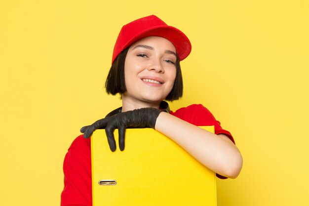 빨간 유니폼 검은 장갑과 미소로 노란색 문서를 들고 빨간 모자에 전면보기 젊은 여성 택배