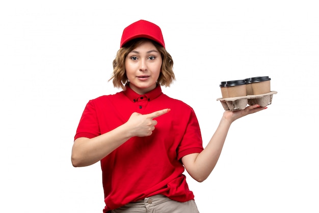 A front view young female courier in uniform holding coffee cups smiling